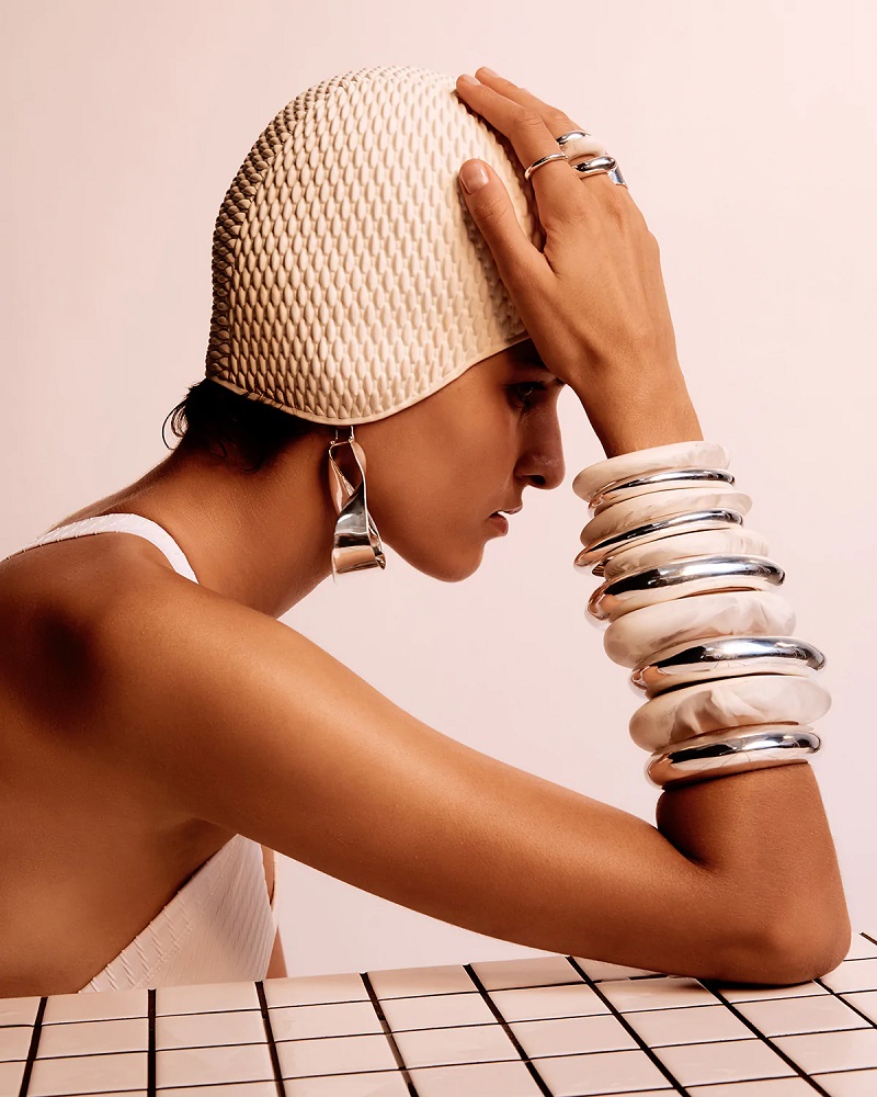 picture of woman wearing hat, designer silver earings and silver bracelets 