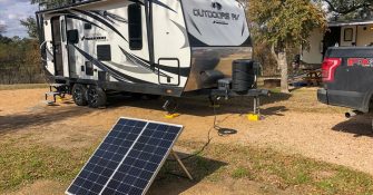 camp and portable solar panel next to it in woods